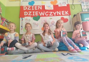 Dziewczynki z grupy biedronek siedzące pod napisem Dzień Dziewczynek.