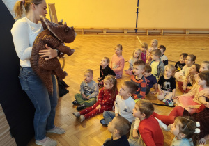 Dzieci siedzące przed planetarium oglądające dinozaura pokazowego.