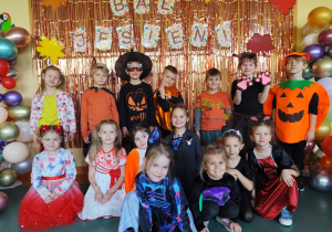 Grupa biedronki pozująca do zdjęcia na tle napisu bal jesieni.