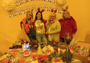 Nauczycielki z przedszkola pozujące do zdjęcia na tle jarmarku świątecznego.