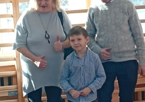 Dzieci pozujące z dziadkami podczas uroczystości przedszkolnej.