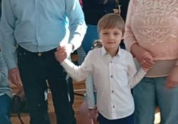 Dzieci pozujące z dziadkami podczas uroczystości przedszkolnej.