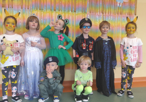 Dzieci z grupy Motylki pozujące przy dekoracji z napisem karnawał.