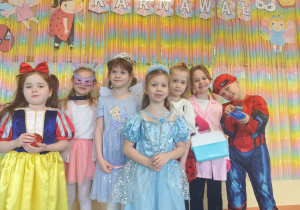 Dzieci z grupy Biedronki pozujące przy dekoracji z napisem karnawał.