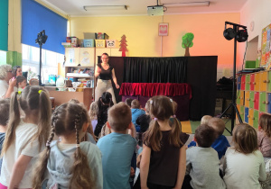 Dzieci z przedszkola siedzące na dywanie podczas trwającego przedstawienia.