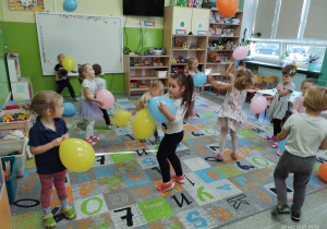Grupka dzieci tańczących na dywanie z balonami