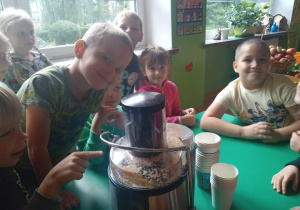 Grupa dzieci przy stoliku pozuje do zdjęcia z sokowirówką