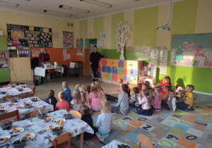 Dzieci siedzące na dywanie. W tle dzbanek z zaparzającą się herbatą.