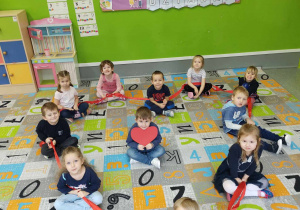Grupa dzieci siedzących na dywanie,tworzących kształt serca.
