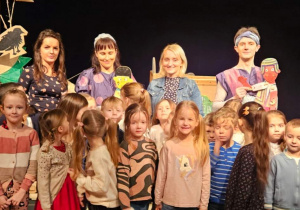 Dzieci z nauczycielami stojące z aktorami na scenie.
