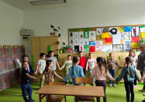 Dzieci stojące w kole z nauczycielem.